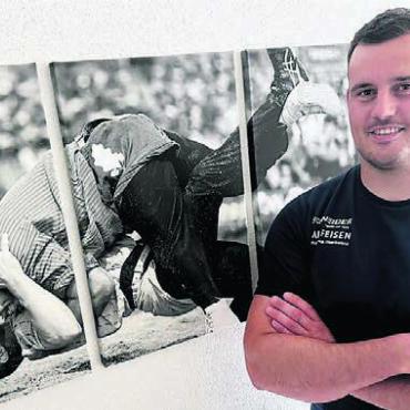 Bevor er noch durchdreht - Bereit für grosse Taten. Joel Strebel steht vor dem Bild, das einen seiner grössten Würfe zeigt: den Sieg gegen Königsanwärter Samuel Giger am ESAF 2022. Bild: spr