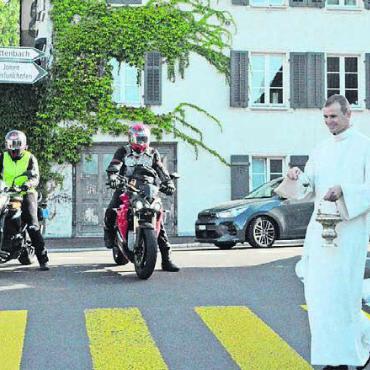Die Strapazen weggefeiert - Pfarreiseelsorger Claudio Gabriel weiht die Strasse ein. Die Motorradfahrer müssen warten.