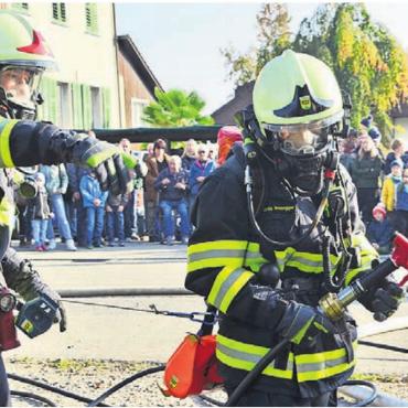 Bereit für den Ernstfall - Unter Atemschutz und mit Schnellangriff geht es vor dem grossen Publikum ins brennende Haus.