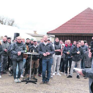 Wo Zukunft aus Holz entsteht - Die Stadelmann & Stutz AG ist in den vergangenen Jahren stark gewachsen und beschäftigt inzwischen über 90 Mitarbeitende, darunter 13 Lernende. Geschäftsführer Richard Stadelmann (rechts) freut sich, mit der Belegschaft auf diesen «historischen Tag» anstossen zu können. Bilder: Chregi Hansen / Visualisierung: zg