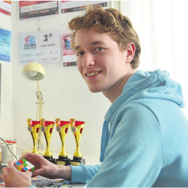 Immer schneller und schneller - Am PC, umgeben von Pokalen, Medaillen und Diplomen, übt Daniel Brem. Jede einzelne Zeit und Ausgangsposition des Würfels wird erfasst. Bild: Annemarie Keusch