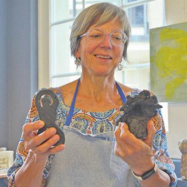 Venus auf 60 andere Arten - Veronika Müller bestaunt zwei der Venusfiguren, die aus einer Handvoll Ton entstanden sind. Bild: Annemarie Keusch