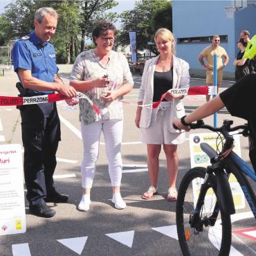 Kinder haben eigene Strasse - Gemeinderätin Milly Stöckli durchschneidet das Band, flankiert von Harald Hirzel, Verkehrsinstruktor der Repol, und Monja van Wegberg, Schulleiterin Mittelstufe. Bild: vaw