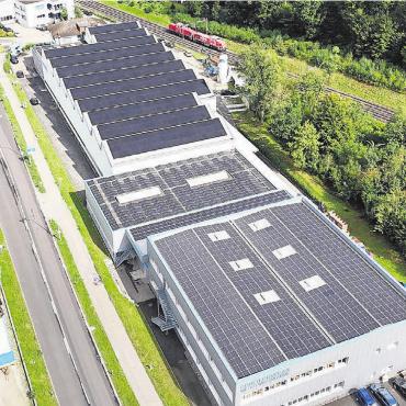 Sonne liefert Produktions-Energie - Alles in Schwarz: PV-Panels bedecken das Dach der Metallwarenfabrik.