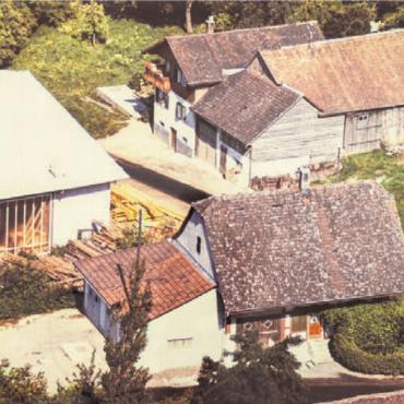 Eigenen Wurzeln treu geblieben - Einst und heute: Links eine Luftansicht aus dem Jahr 1965 mit dem Saxehus (vorne), dem Elternhaus (hinten) und einem Teil der Holzbauhalle. Das Bild rechts zeigt eine Drohnenaufnahme des gesamten Betriebsgeländes von 2025.