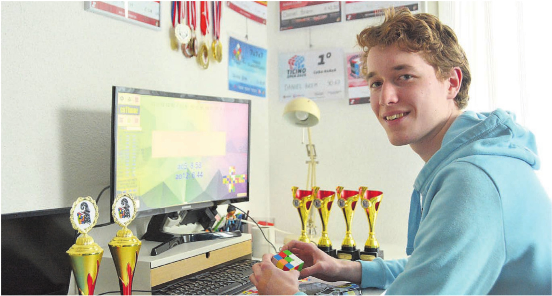Am PC, umgeben von Pokalen, Medaillen und Diplomen, übt Daniel Brem. Jede einzelne Zeit und Ausgangsposition des Würfels wird erfasst. Bild: Annemarie Keusch - Das Bild wird blockiert. – Möglicherweise durch einen aktiven Adblocker.