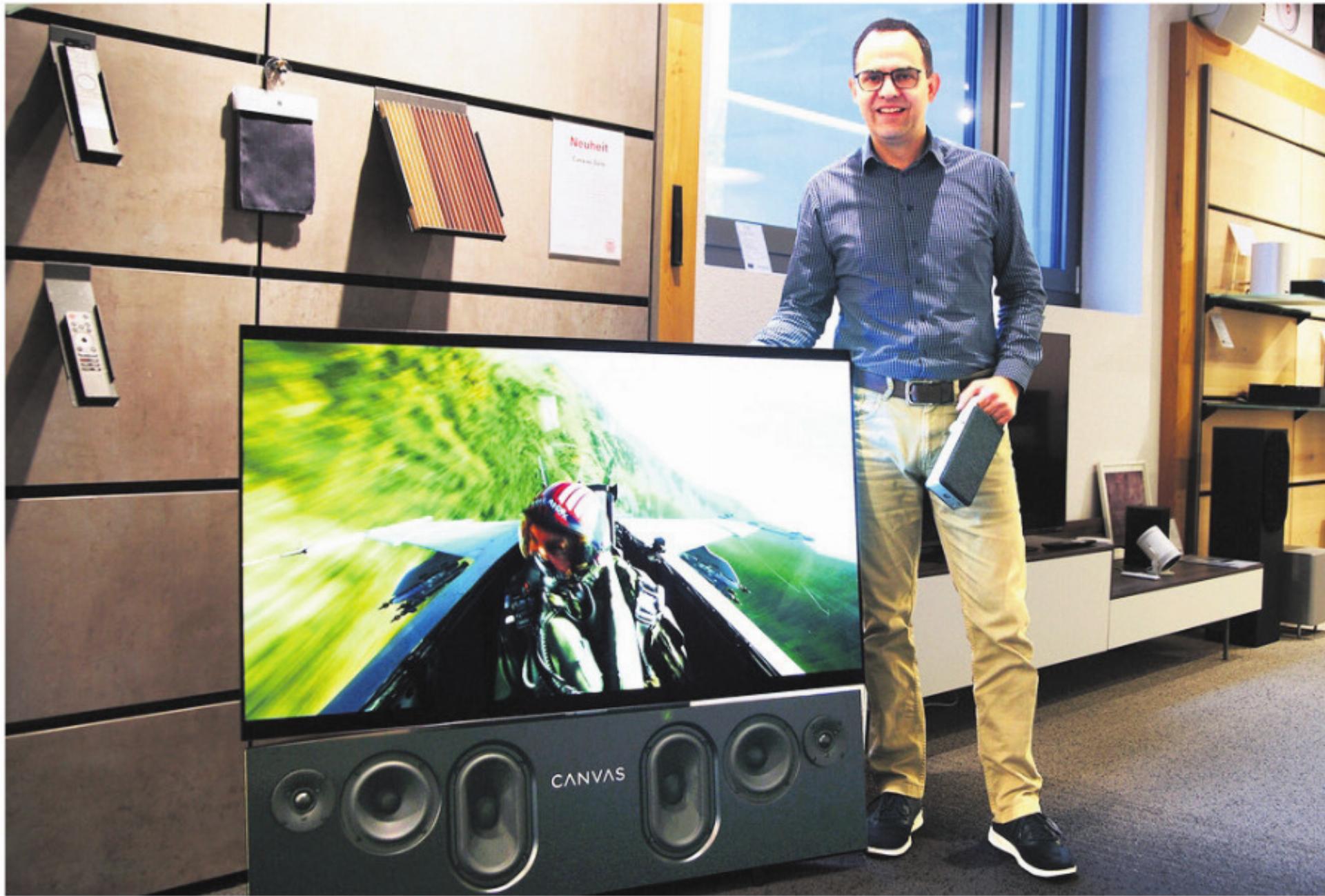 Serge Müller, Geschäftsführer von Tschachtli Klang & Bild, demonstriert im Showroom an der Breitistrasse 6 in Wohlen die CANVAS HiFi Soundbar (unterhalb des Bildschirms) sowie in der linken Hand den kabellosen Sprachverstärker OSKAR, der flexibel in der ganzen Wohnung einsetzbar ist. Bild: zg - Das Bild wird blockiert. – Möglicherweise durch einen aktiven Adblocker.