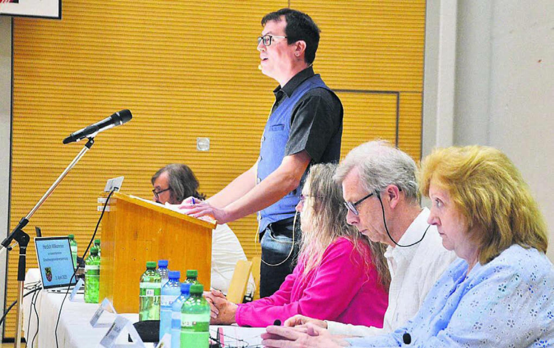 Gemeindeammann Alain Maître (stehend) begrüsste zur Gemeindeversammlung in der Turnhalle, umringt von den Gemeinderats-Kolleginnen und -Kollegen. Von vorne: Vivienne Graw, Cristian Canis, Barbara Weber und Roland Geier. Bild: Thomas Stöckli
