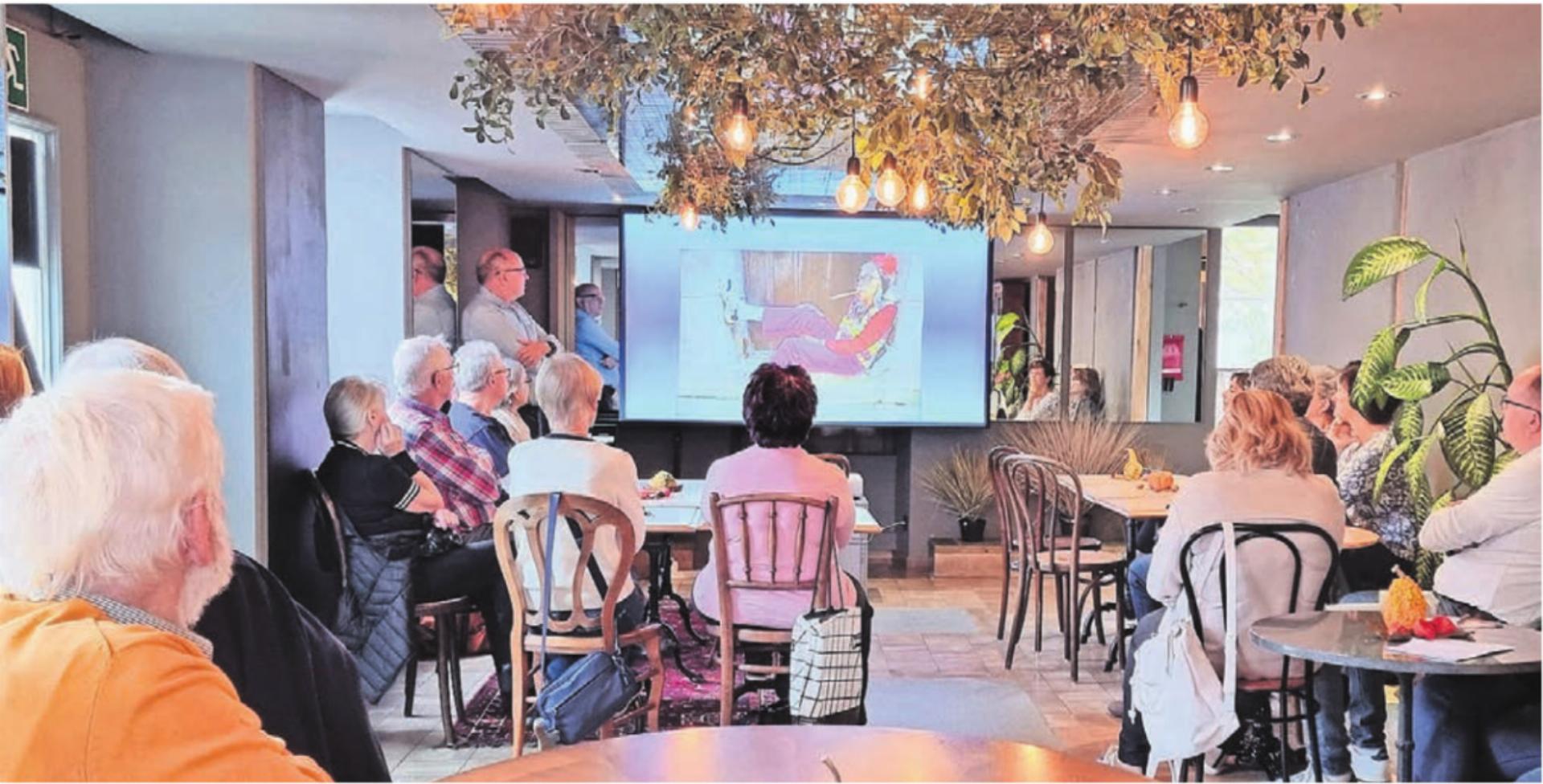 Das interessierte Publikum amüsierte sich ob dem Bild der 100-jährigen mit Zigarre. Auch so kann sich Alter zeigen, wusste Simon Feldhaus, neben Leinwand, links. Bild: vaw - Das Bild wird blockiert. – Möglicherweise durch einen aktiven Adblocker.