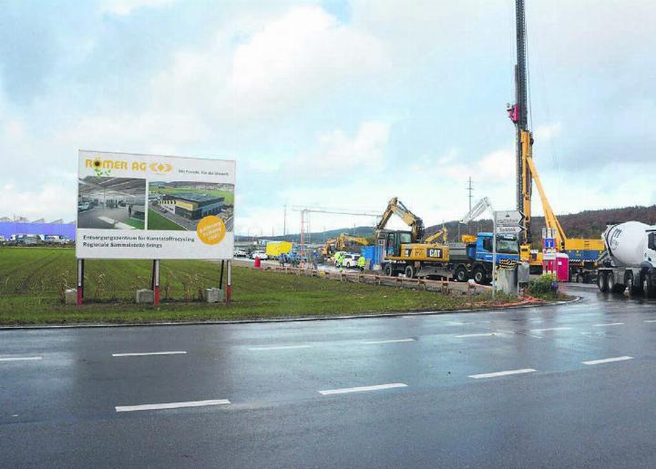 Direkt neben der Nutzenbachstrasse wird mit Hochdruck an der neuen Sammelstelle gearbeitet. Dabei kommt die schweizweit grösste Maschine für Pfählungen zum Einsatz. Bild: Chregi Hansen / Visualisierung: zg