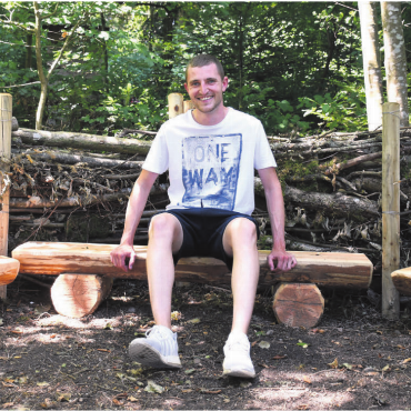 Es lohnt sich, sich zu engagieren - Corsin Stöckli sitzt zur Probe auf dem neuen Waldsofa beim Wasserturm in Aristau. Die Schule Aristau und der Forstbetrieb haben es im Frühsommer erbaut. Die sechs Bänkli zum Sofa hat die Ortsbürgergemeinde gesponsert. «Hier wird das Wirken der Ortsbürger sichtbar», sagt Stöckli, der sich freut, dass sie für die Schule dieses externe Zimmer mitgestalten konnten. Bild: Verena Anna Wigger